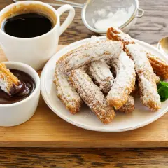 Churros przepis: złociste, posypane cukrem pudrem, z gorącą czekoladą i kawą. Idealne na deser.