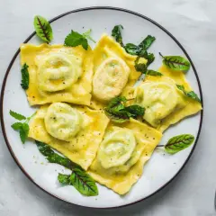 Pyszne ravioli z zielonym nadzieniem, udekorowane listkami. Idealny przepis na ravioli dla każdego smakosza.