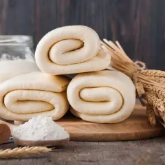Rolowane ciasto francuskie, choć po terminie, wygląda apetycznie. Obok kłosy zbóż i mąka.