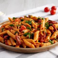 Pyszny makaron penne z sosem pomidorowym, kawałkami suszonych pomidorów i świeżą natką pietruszki.