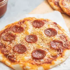 Pyszna pizza z tortilli z pepperoni i serem, obok sos w miseczce i łyżeczka.
