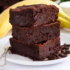 Pyszne brownie z bananami, ułożone na talerzu z kawowymi ziarnami. Idealne na deser!