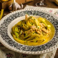 Tagliatelle w kremowym sosie curry z kawałkami kurczaka i porem, udekorowane szczypiorkiem.