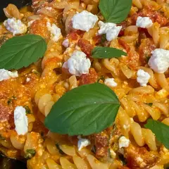 Makaron fusilli z sosem pomidorowym, kawałkami sera feta i listkami bazylii. Pyszne danie, które zachwyci każdego miłośnika pomidorów z fetą.