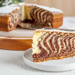 Pyszne ciasto zebra z cukrem pudrem, z widocznym kawałkiem na talerzyku.