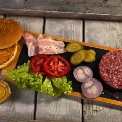 Wszystko, co do burgera: bułka, surowe mięso, boczek, pomidory, sałata, ogórki, cebula i musztarda.