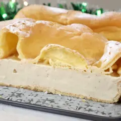 Pyszny deser z ciasta ptysiowego wypełniony kremem budyniowym, ozdobiony cukrem pudrem.