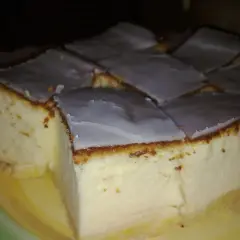Kawałki bardzo puszystego sernika z wiaderka, polane lukrem, na talerzu.