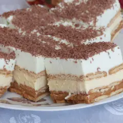Pyszny placek bez pieczenia z kremem i karmelem, posypany wiórkami czekoladowymi. Idealny na deser.