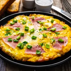 Pyszny omlet z szynką i serem, posypany szczypiorkiem. Idealny pomysł na śniadanie, jak zrobić omlet z szynką i serem.