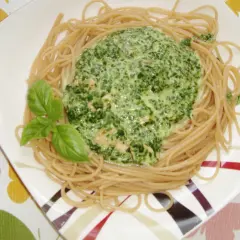 Pyszny makaron ze szpinakiem w kremowym sosie, udekorowany listkami bazylii.