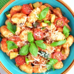 Pyszne gnocchi z sosem pomidorowym, cukinią, pomidorkami koktajlowymi i bazylią, posypane parmezanem.