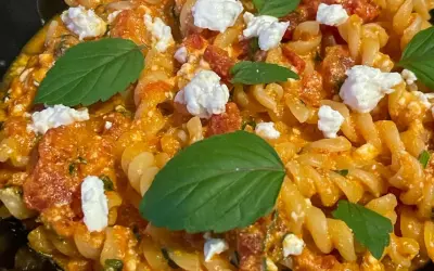 Makaron fusilli z sosem pomidorowym, kawałkami sera feta i listkami bazylii. Pyszne danie, które zachwyci każdego miłośnika pomidorów z fetą.