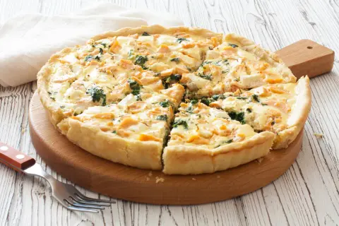 Pyszna tarta z łososiem, szpinakiem i serem feta, pokrojona na kawałki, gotowa do podania.