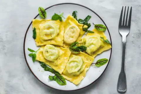 Pyszne ravioli z zielonym nadzieniem, udekorowane listkami. Idealny przepis na ravioli dla każdego smakosza.