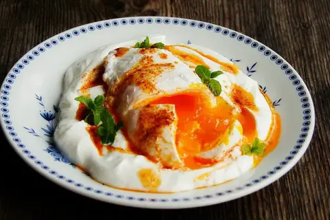 Jajka po turecku na kremowym jogurcie, posypane papryką i ozdobione miętą. Pyszne śniadanie!