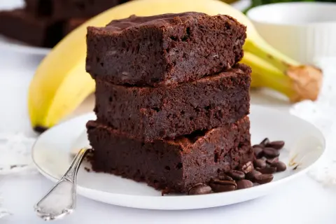 Pyszne brownie z bananami, ułożone na talerzu z kawowymi ziarnami. Idealne na deser!