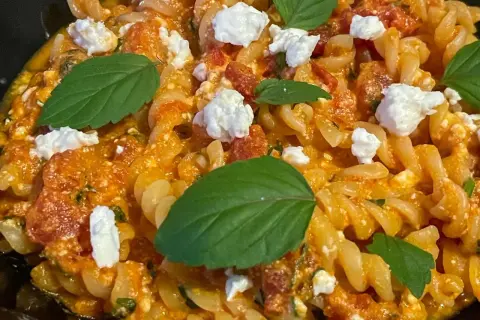 Makaron fusilli z sosem pomidorowym, kawałkami sera feta i listkami bazylii. Pyszne danie, które zachwyci każdego miłośnika pomidorów z fetą.