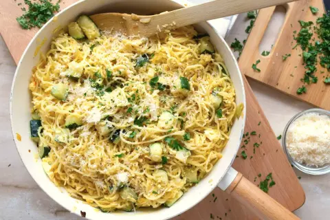 Pyszny makaron z cukinią, posypany parmezanem i świeżą natką pietruszki, gotowy do podania.