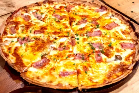Pyszna pizza z patelni bez drożdży, z ciągnącym serem, kawałkami boczku i szczypiorkiem. Idealna na szybki obiad.