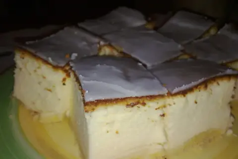 Kawałki bardzo puszystego sernika z wiaderka, polane lukrem, na talerzu.