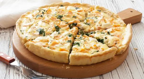 Pyszna tarta z łososiem, szpinakiem i serem feta, pokrojona na kawałki, gotowa do podania.