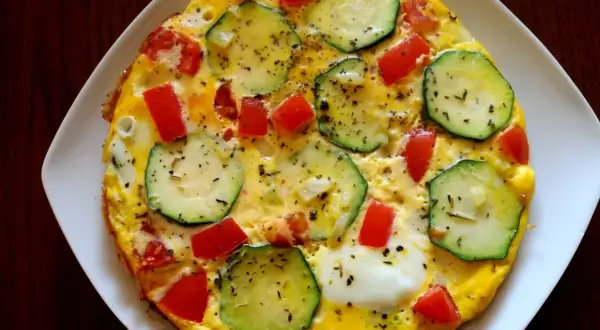 Pyszna cukinia na śniadanie w postaci omletu z pomidorami, posypana ziołami. Idealny początek dnia!