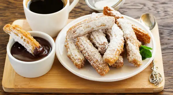 Churros przepis: złociste, posypane cukrem pudrem, z gorącą czekoladą i kawą. Idealne na deser.