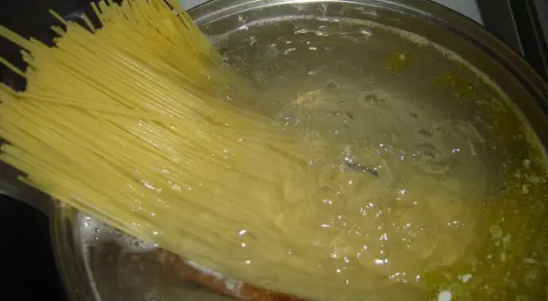 Długi makaron spaghetti gotuje się w bulgoczącej wodzie. Czas, ile gotować makaron, zależy od jego grubości.