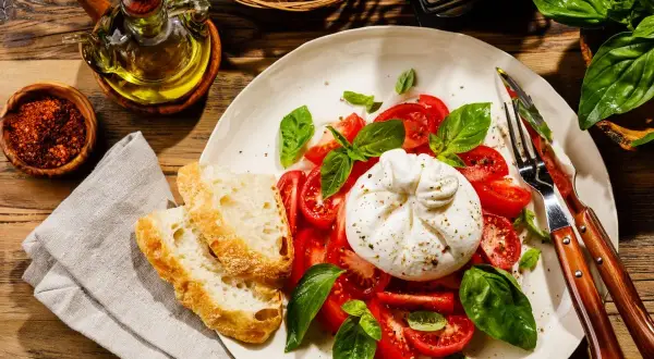 Pyszna burrata co to? Kremowy ser z pomidorami, bazylią i chrupiącym pieczywem. Idealna na lekki posiłek.