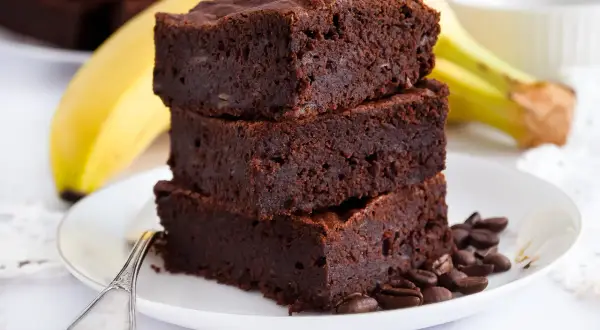 Pyszne brownie z bananami, ułożone na talerzu z kawowymi ziarnami. Idealne na deser!
