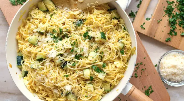 Pyszny makaron z cukinią, posypany parmezanem i świeżą natką pietruszki, gotowy do podania.