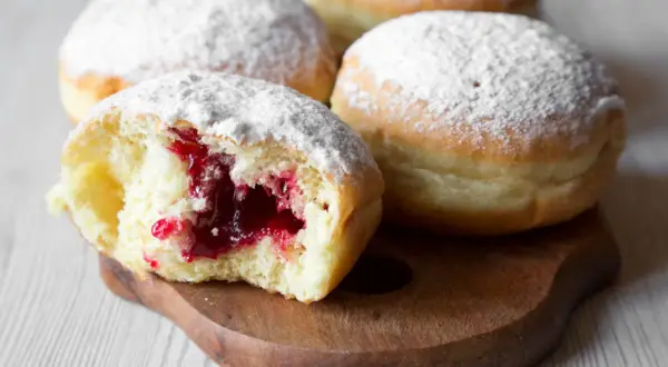Puszyste pączki z dżemem, posypane cukrem pudrem. Idealne na tłusty czwartek, zgodnie z tradycyjnym paczki przepis.