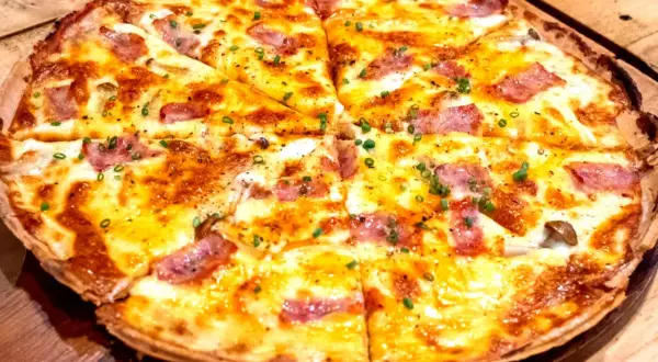 Pyszna pizza z patelni bez drożdży, z ciągnącym serem, kawałkami boczku i szczypiorkiem. Idealna na szybki obiad.