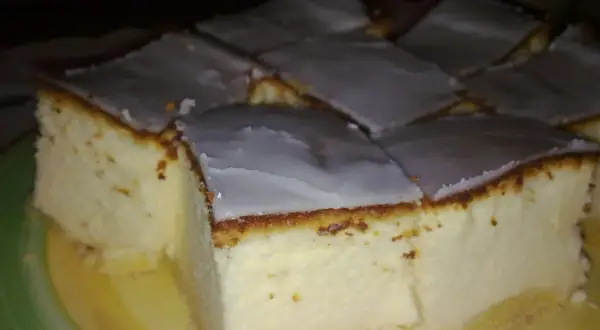 Kawałki bardzo puszystego sernika z wiaderka, polane lukrem, na talerzu.