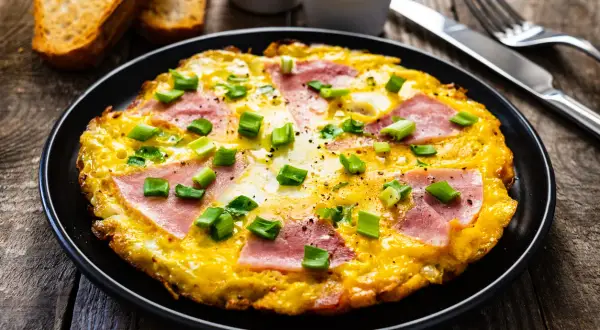 Pyszny omlet z szynką i serem, posypany szczypiorkiem. Idealny pomysł na śniadanie, jak zrobić omlet z szynką i serem.