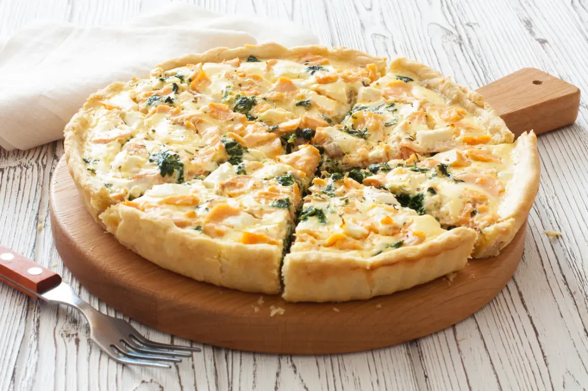 Pyszna tarta z łososiem, szpinakiem i serem feta, pokrojona na kawałki, gotowa do podania.