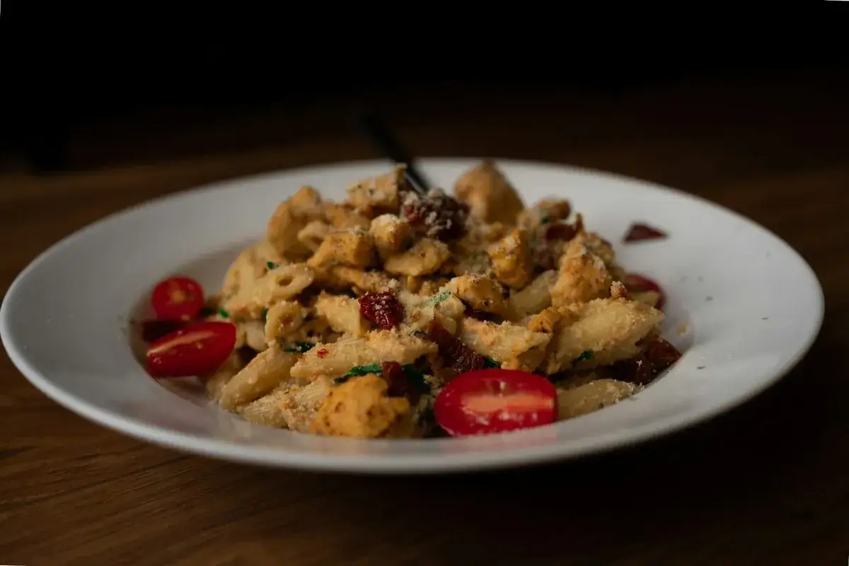 Penne z kurczakiem i suszonymi pomidorami w kremowym sosie z mascarpone, posypane parmezanem.