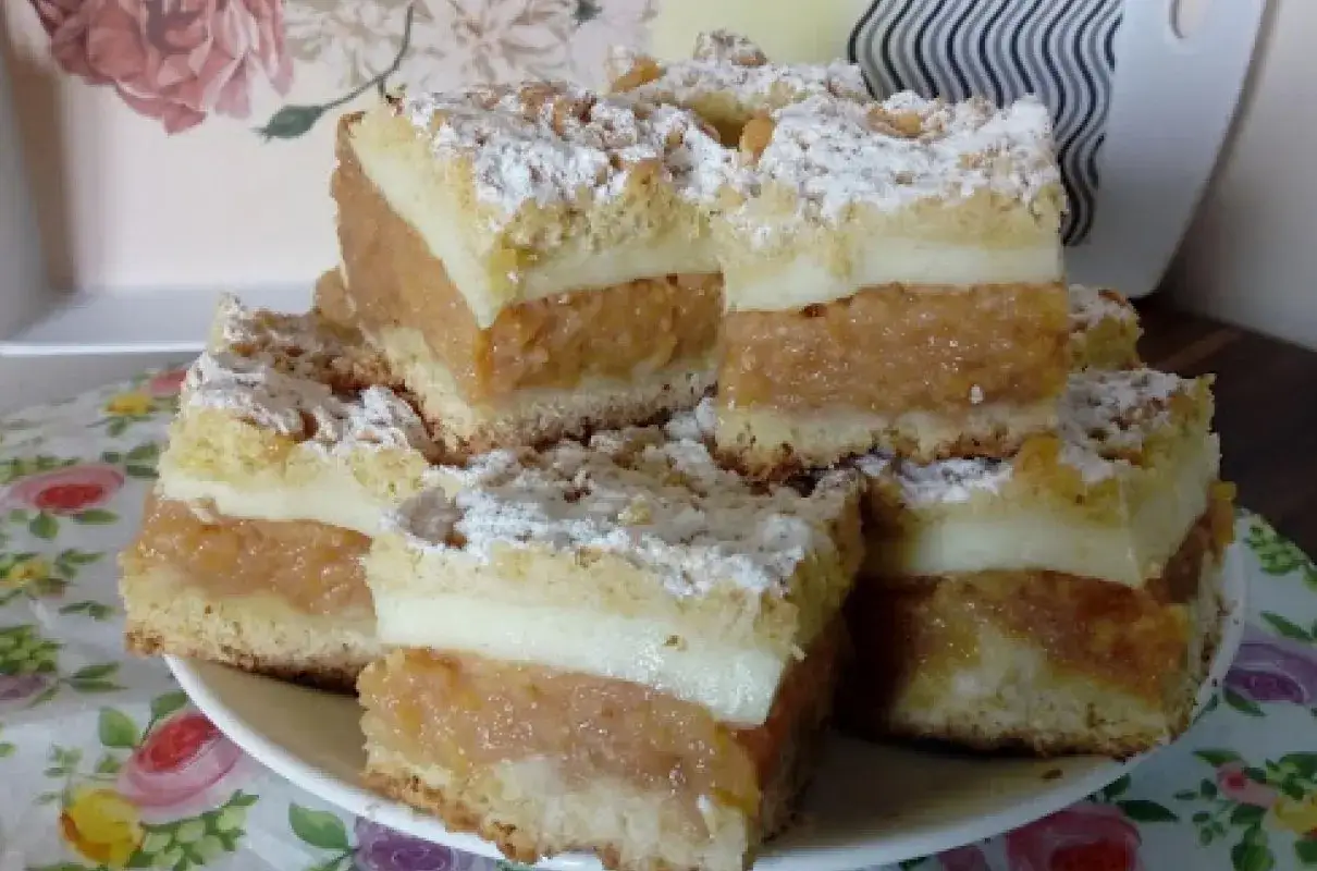Pyszna szarlotka z budyniem, pokrojona na kwadraty, posypana cukrem pudrem. Idealna na deser.