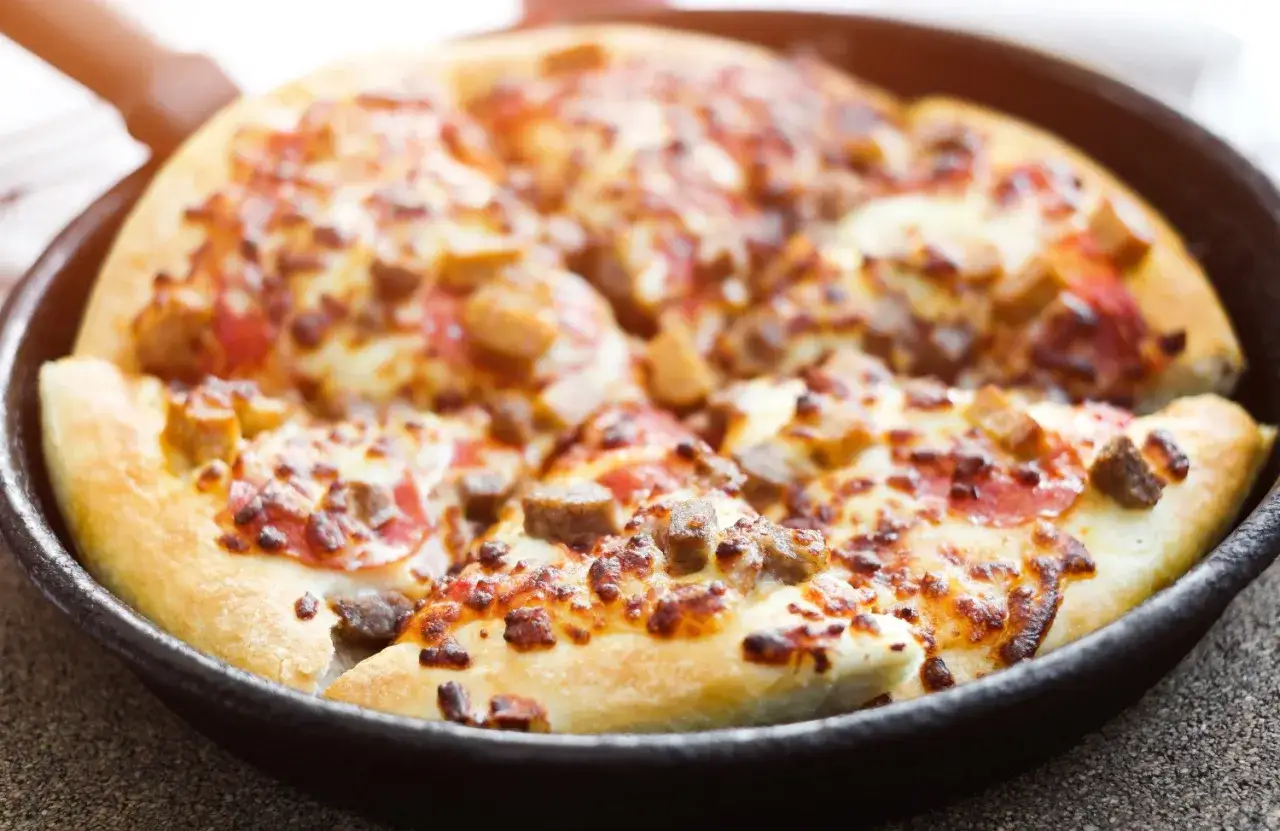 Pyszna pizza z patelni bez drożdży, z ciągnącym serem i kawałkami mięsa, gotowa do podania.