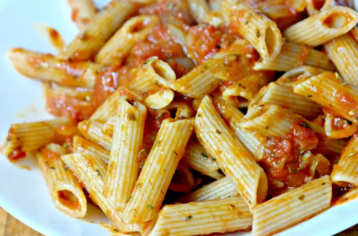 Penne rigate w bogatym sosie pomidorowym, doprawione ziołami. Pyszny makaron z sosem pomidorowym, gotowy do podania.
