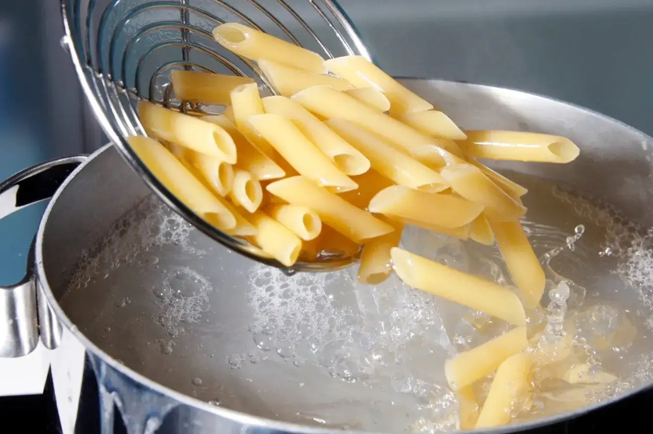 Makaron penne wrzucony do wrzącej wody. Zobacz, ile gotować makaron, by był idealny.