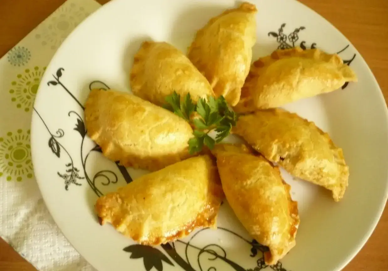 Złociste pierogi z kurkami, okrasa z natki pietruszki. Pyszne danie na talerzu.