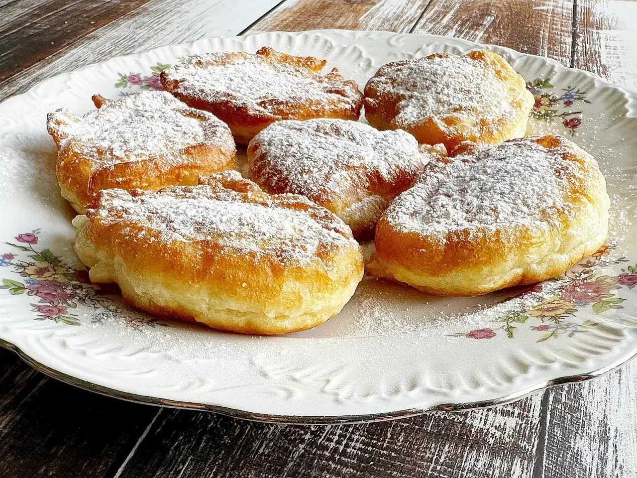 Puszyste racuchy na jogurcie, posypane cukrem pudrem, kuszą swoim złotym kolorem i delikatnością. Idealne na słodkie śniadanie lub deser.