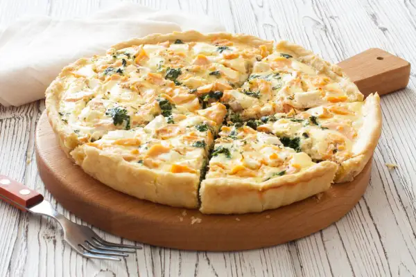 Pyszna tarta z łososiem, szpinakiem i serem feta, pokrojona na kawałki, gotowa do podania.