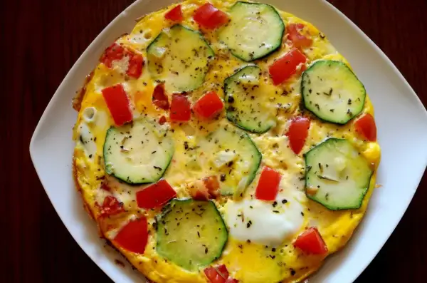 Pyszna cukinia na śniadanie w postaci omletu z pomidorami, posypana ziołami. Idealny początek dnia!