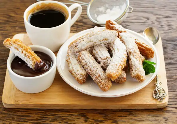 Churros przepis: złociste, posypane cukrem pudrem, z gorącą czekoladą i kawą. Idealne na deser.
