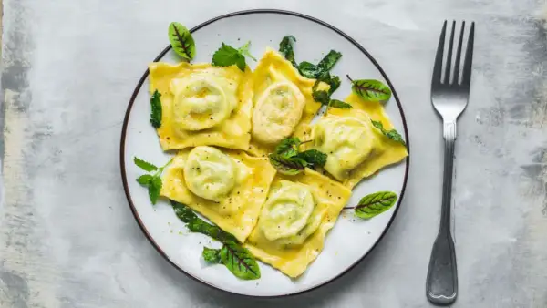 Pyszne ravioli z zielonym nadzieniem, udekorowane listkami. Idealny przepis na ravioli dla każdego smakosza.