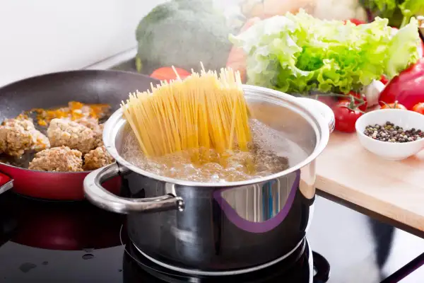 Gotujesz spaghetti? Aby makaron się nie sklejał, dodaj łyżkę oleju do wrzącej wody. Obok smażą się klopsiki.