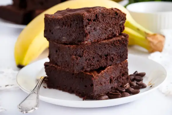 Pyszne brownie z bananami, ułożone na talerzu z kawowymi ziarnami. Idealne na deser!